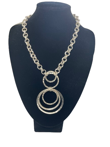 Silver necklace with circular pendant on a black mannequin bust