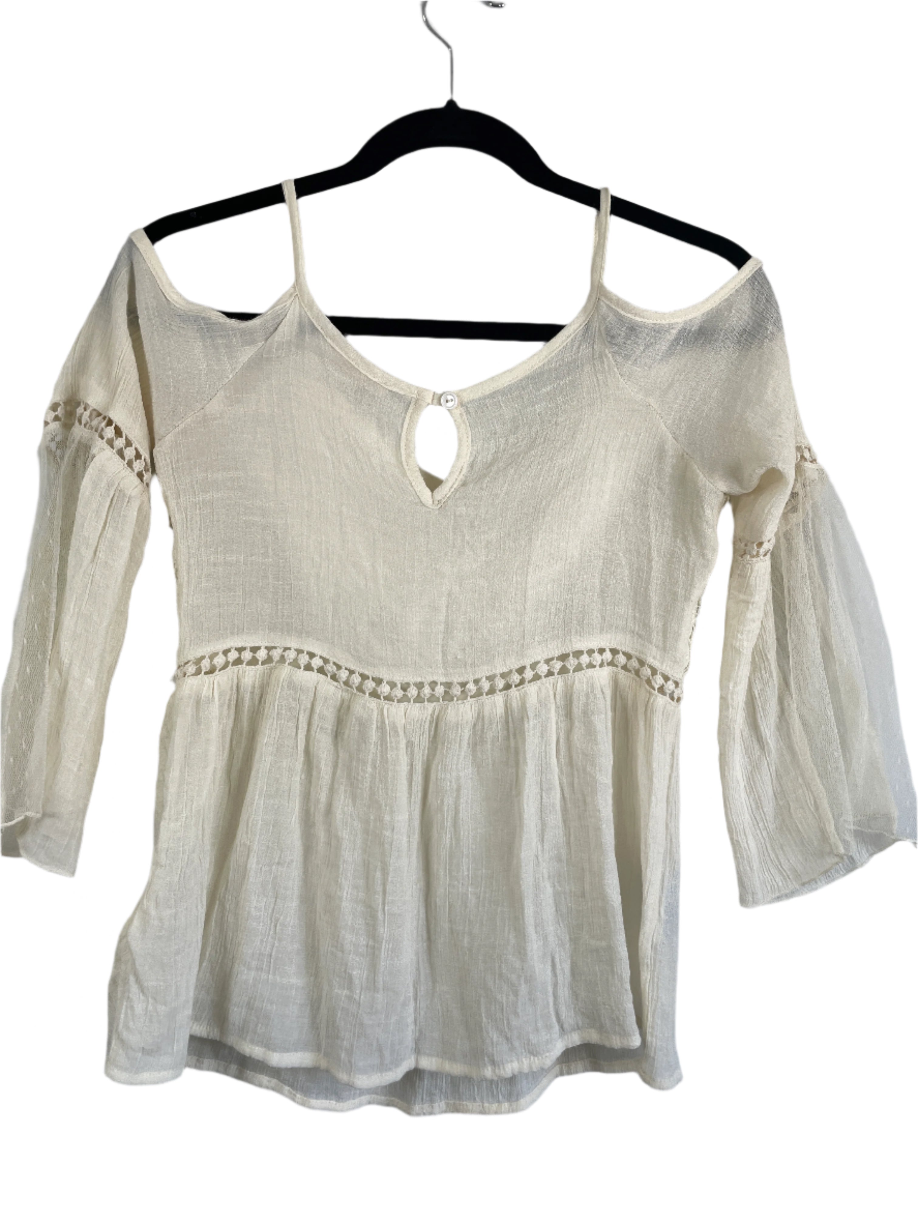 Light-colored top on a hanger against a gray background