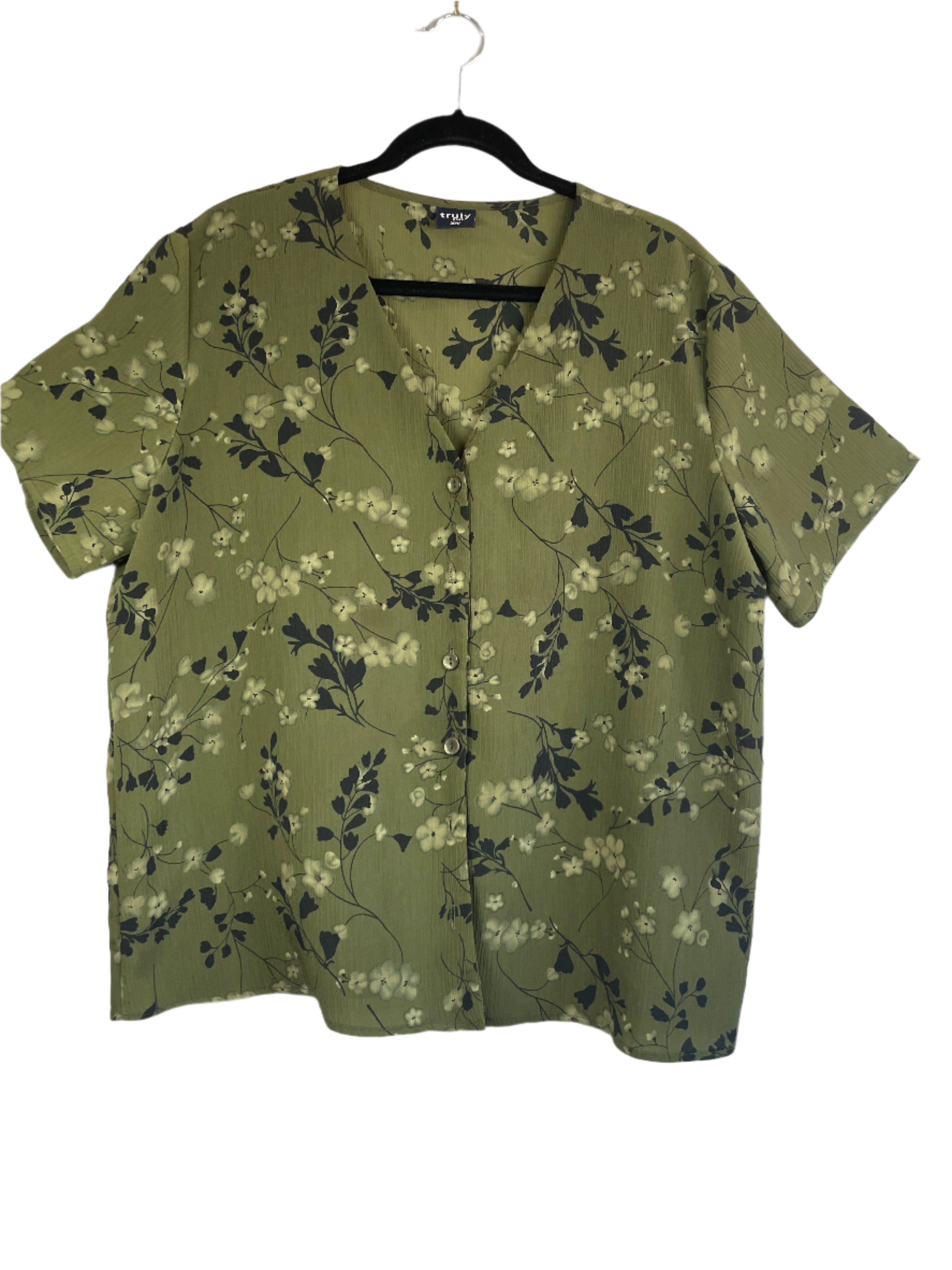 Green floral short-sleeve crinkle blouse by Truly Plus, size 20W, front view on hanger.