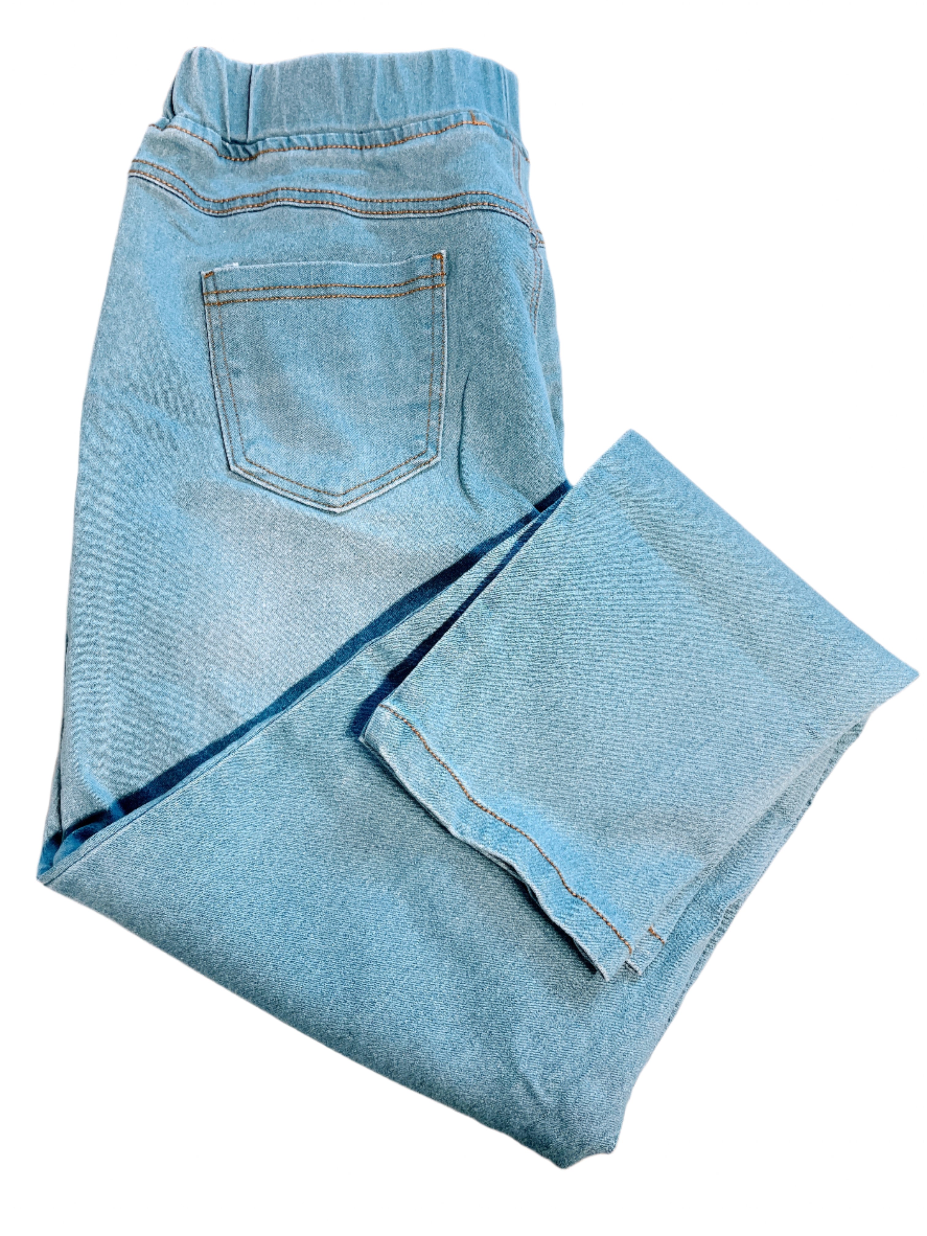 Folded blue jeans on a white surface