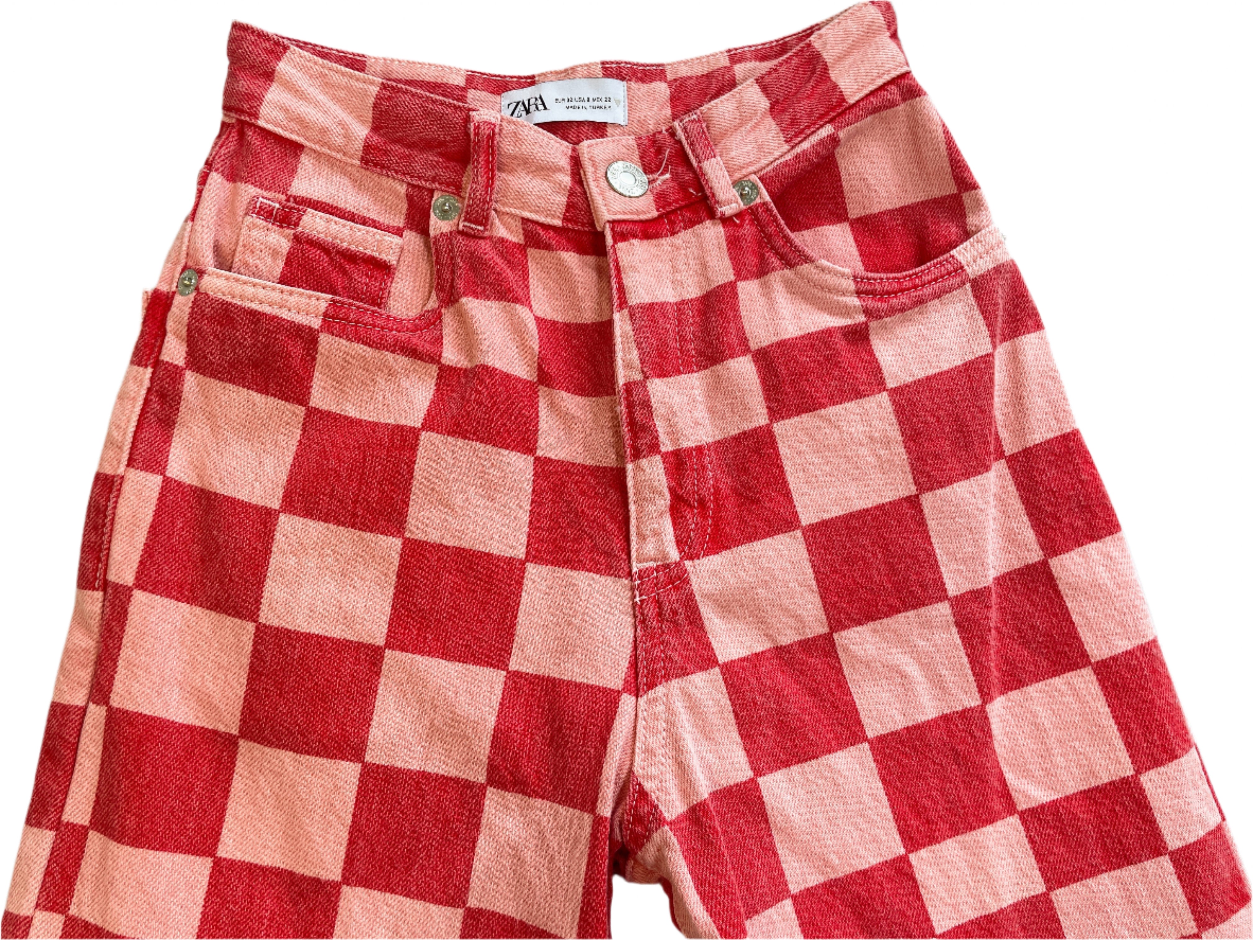 Red and pink checkered jeans on a light gray surface