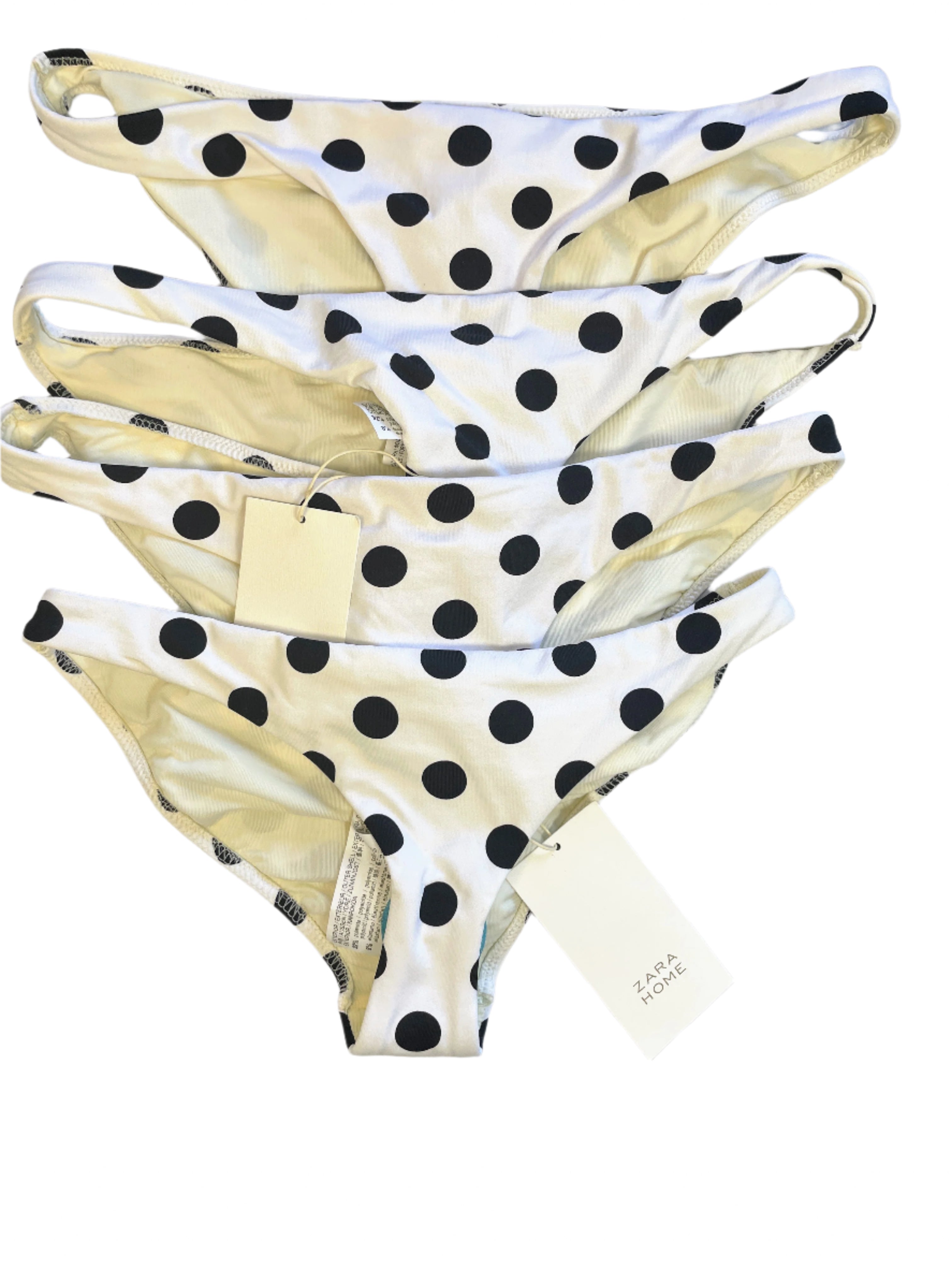 Set of polka dot bikini bottoms on a white surface with a visible brand tag.