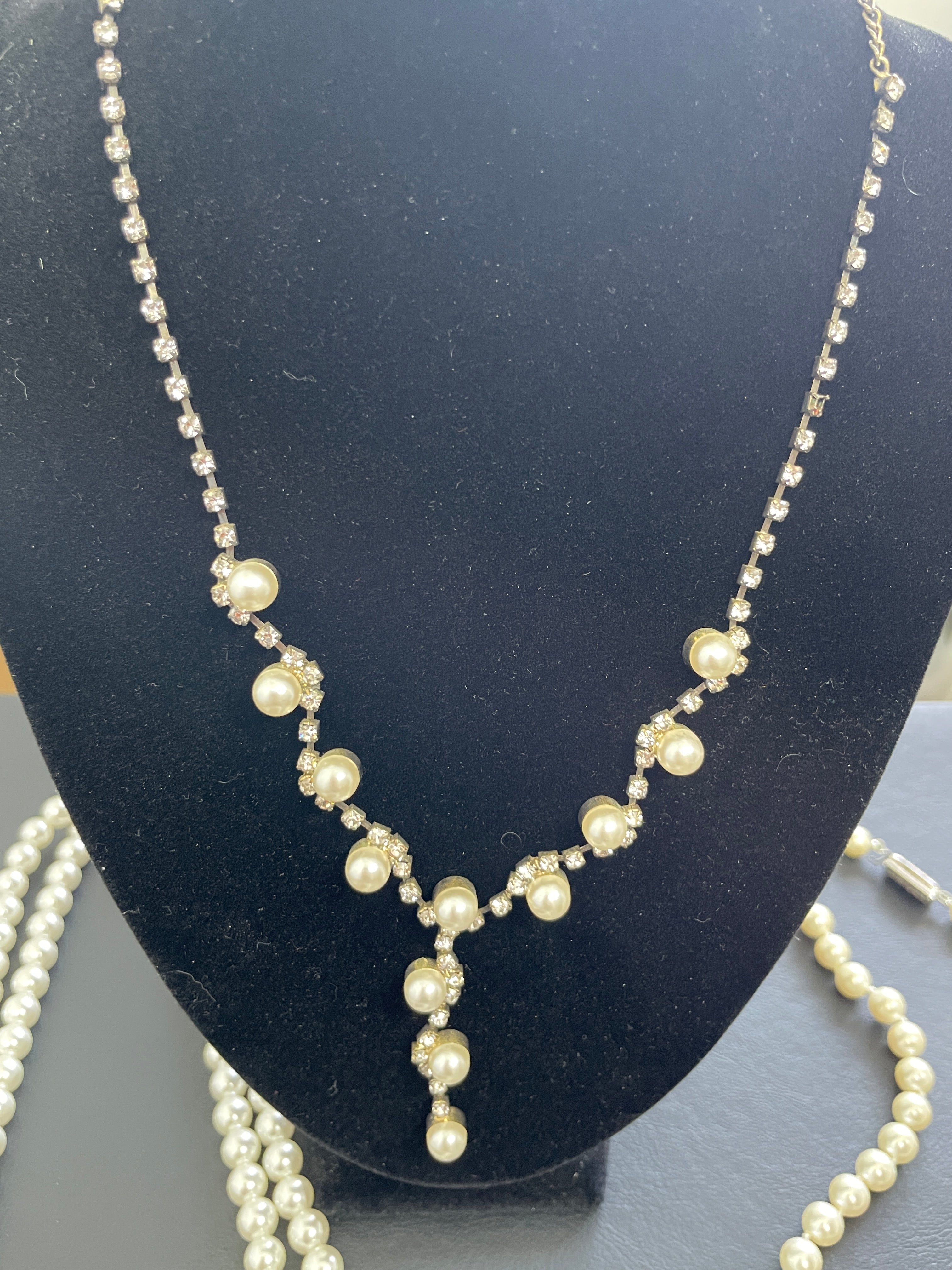 Pearl necklace on a black stand with a gray background