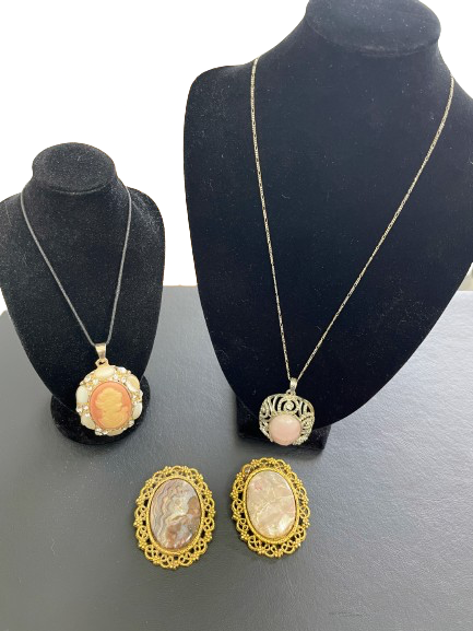 Jewelry set with necklaces and brooches  on black mannequin busts.