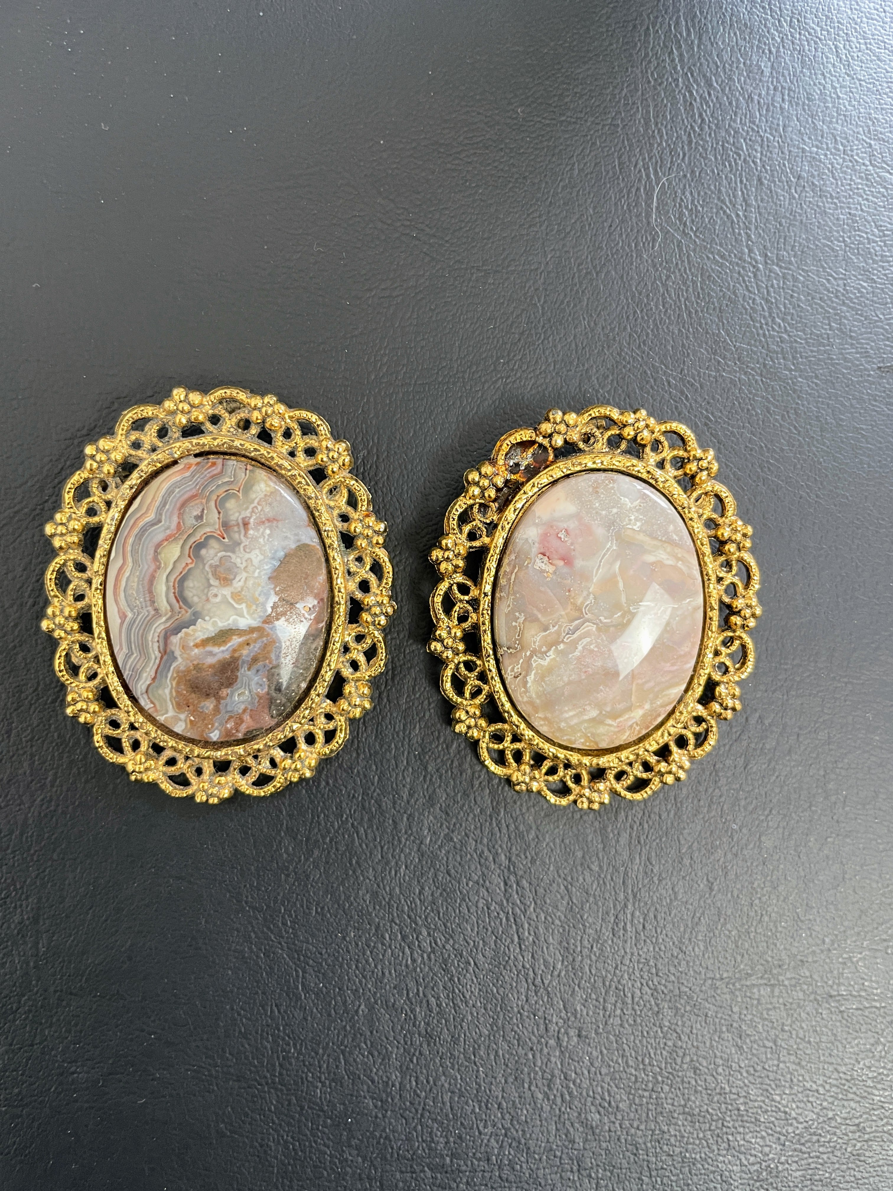 Pair of gold-framed brooches with cameo design on a black background