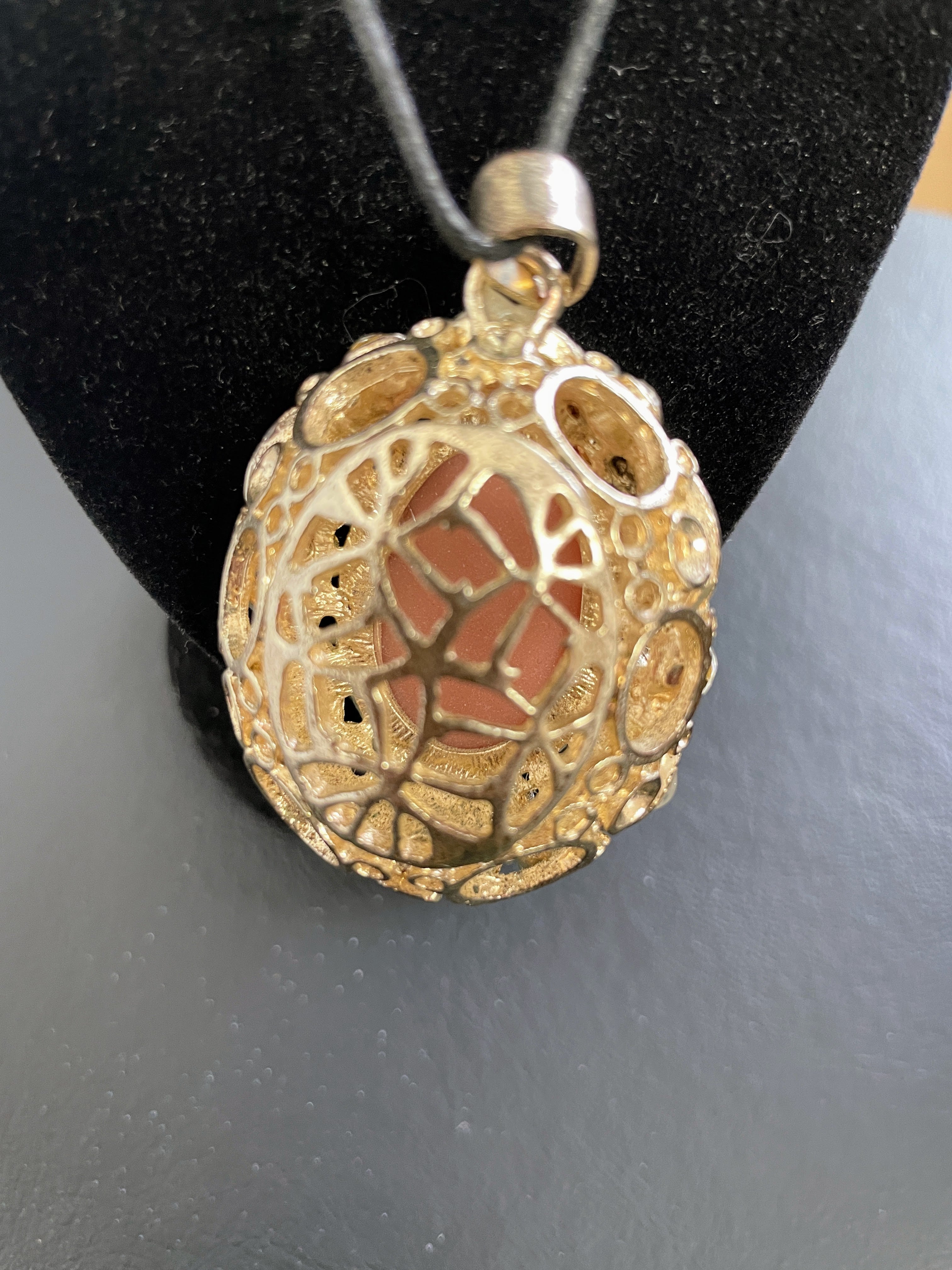 Gold and red stone pendant on a black stand