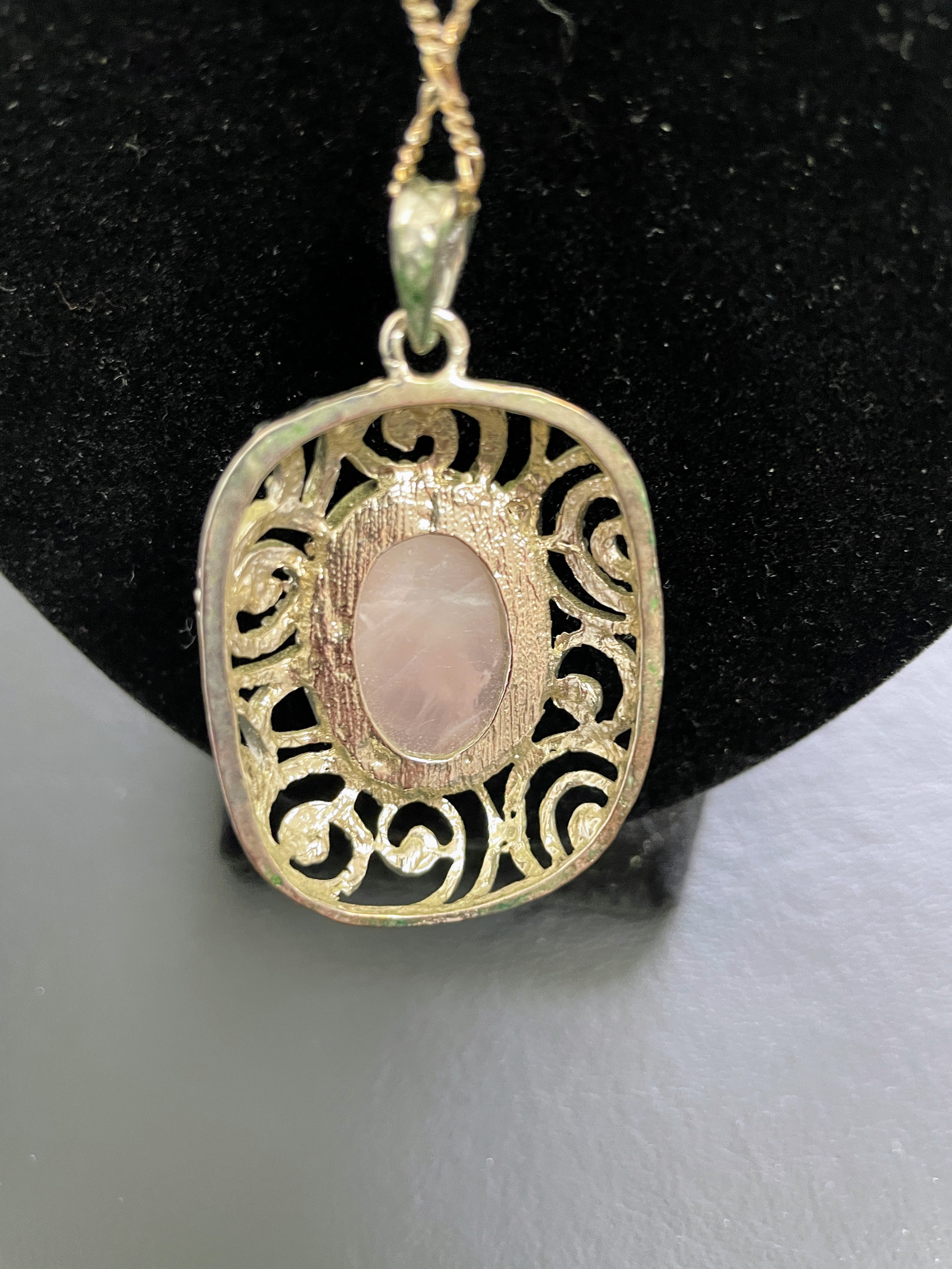 Gold pendant with pink stone on a black background