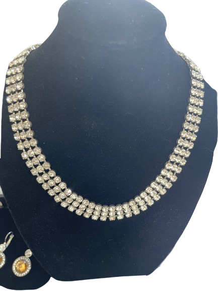 Necklace and earrings set on a black stand