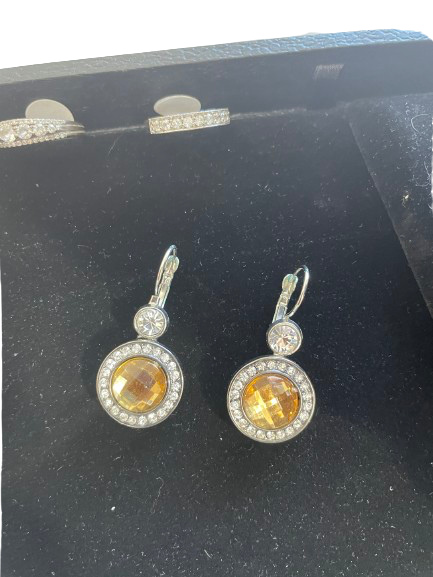 Pair of earrings with yellow gemstones and clear stones on a black background