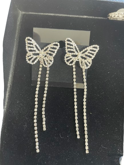 Butterfly-shaped earrings with dangling elements on a black background