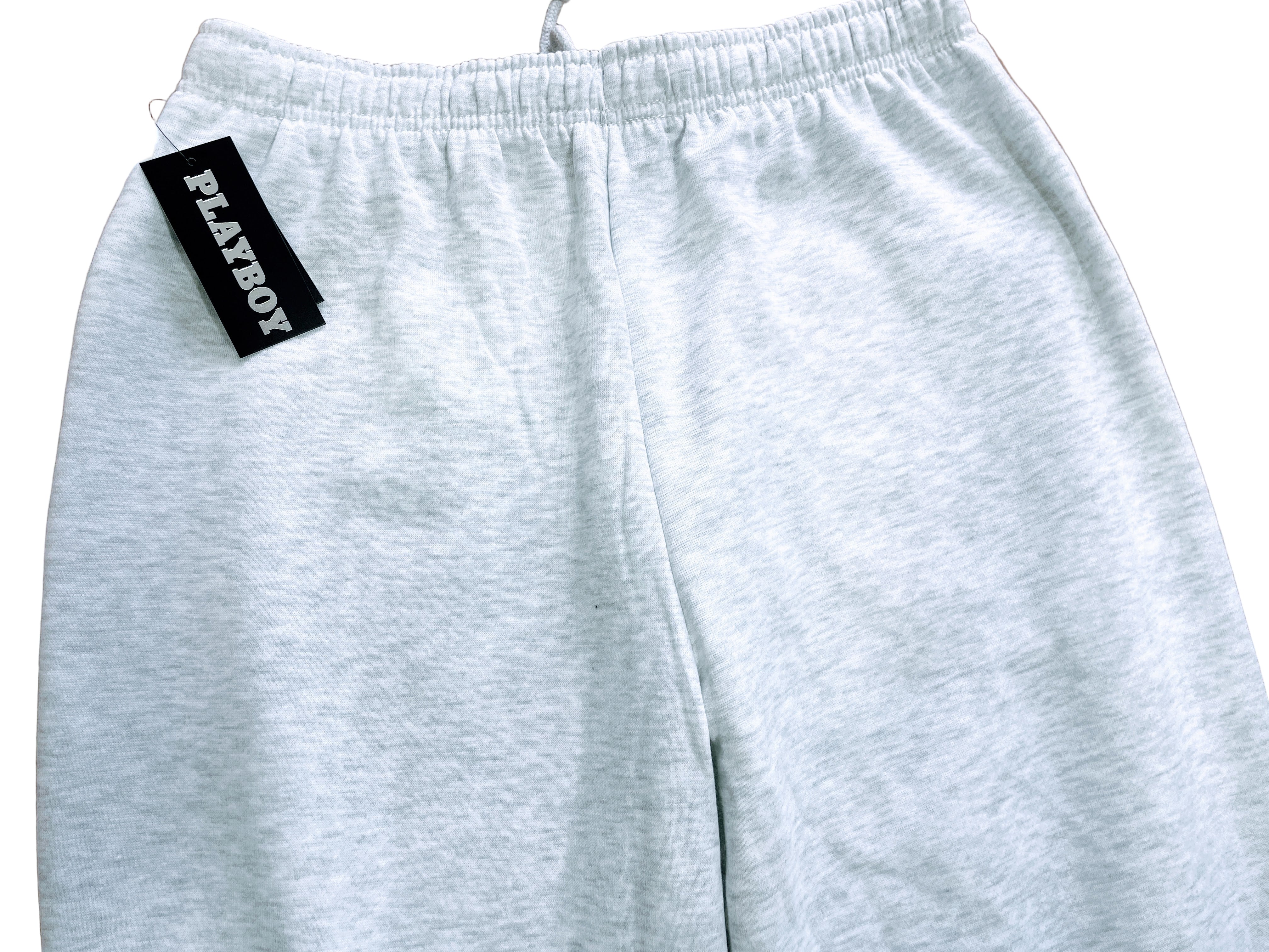 Gray sweatpants with a Playboy tag on a brown surface