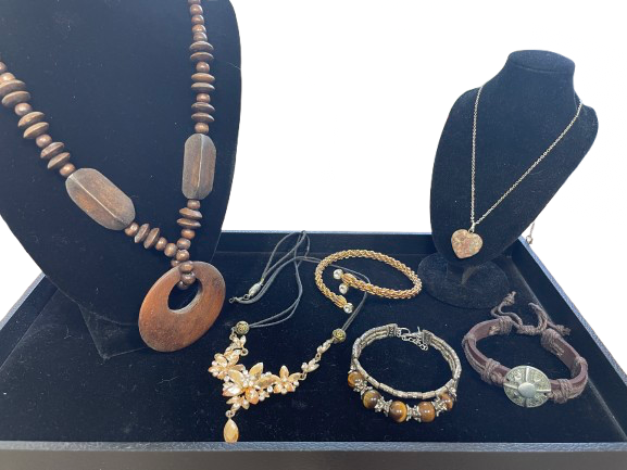 Collection of jewelry including necklaces and bracelets on a dark blue stand.