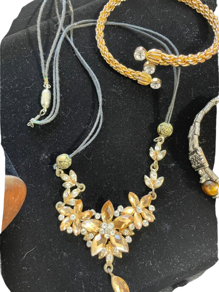 Gold necklace with floral design on a dark stone surface
