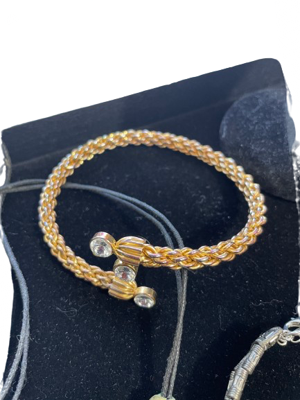 Gold bracelet with decorative elements on a black textured surface