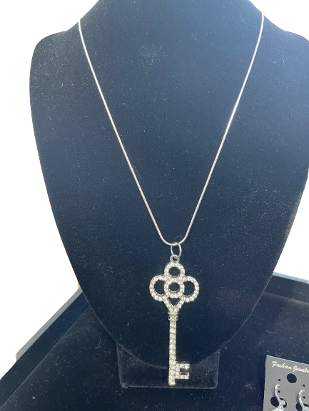 Silver key-shaped pendant necklace on a black stand