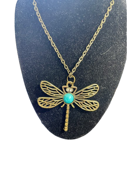 Gold dragonfly necklace with turquoise stone on a black stand