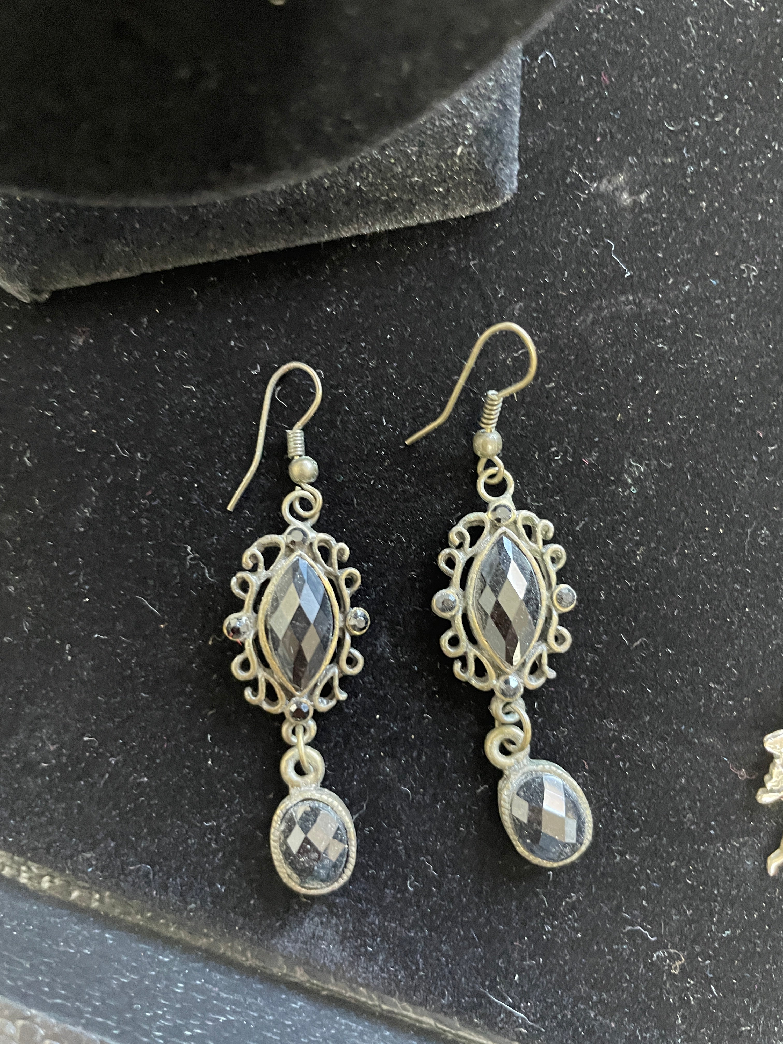 Pair of silver earrings with gemstone-like stones on a dark surface