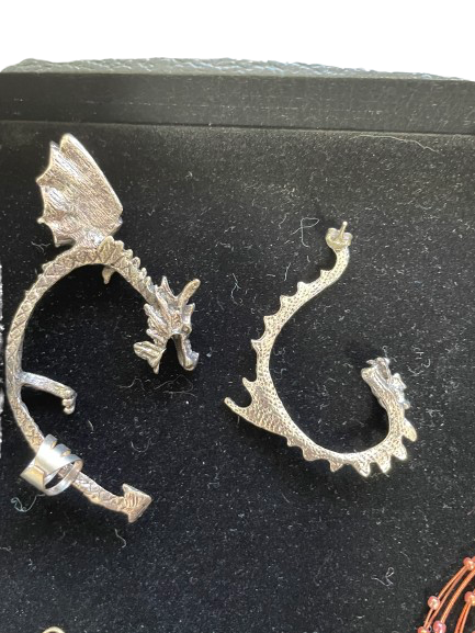 Silver dragon-shaped earrings on a black background
