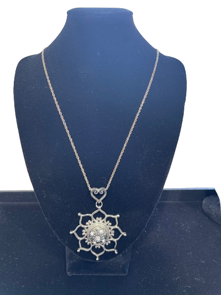 Silver necklace with a star-shaped pendant on a blue stand