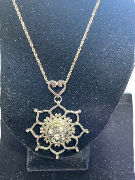 Silver snowflake pendant necklace on a black stand