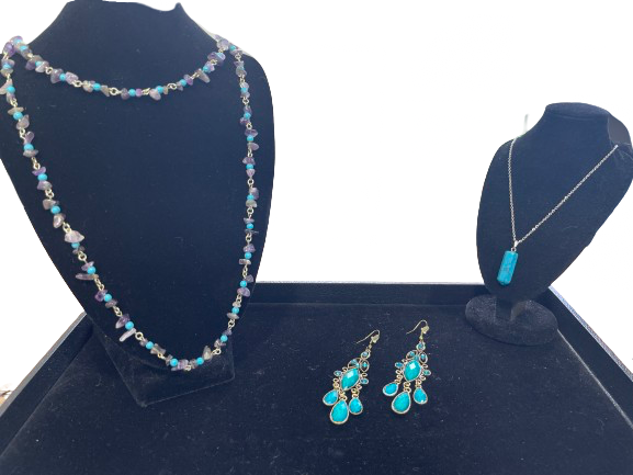 Jewelry set with necklace, earrings, and pendant on a blue stand.