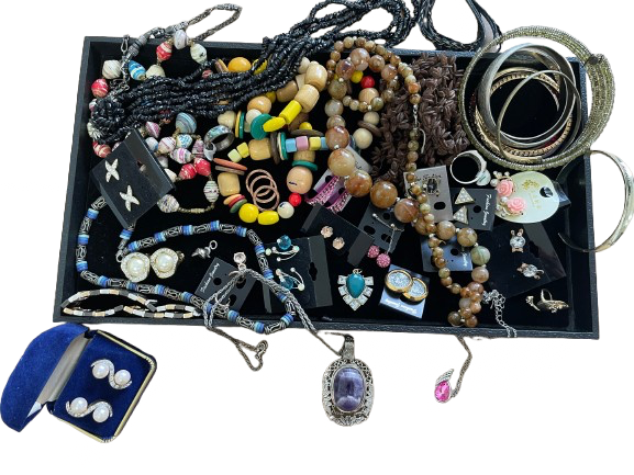 Assorted jewelry including necklaces, bracelets, and pendants on a black tray.