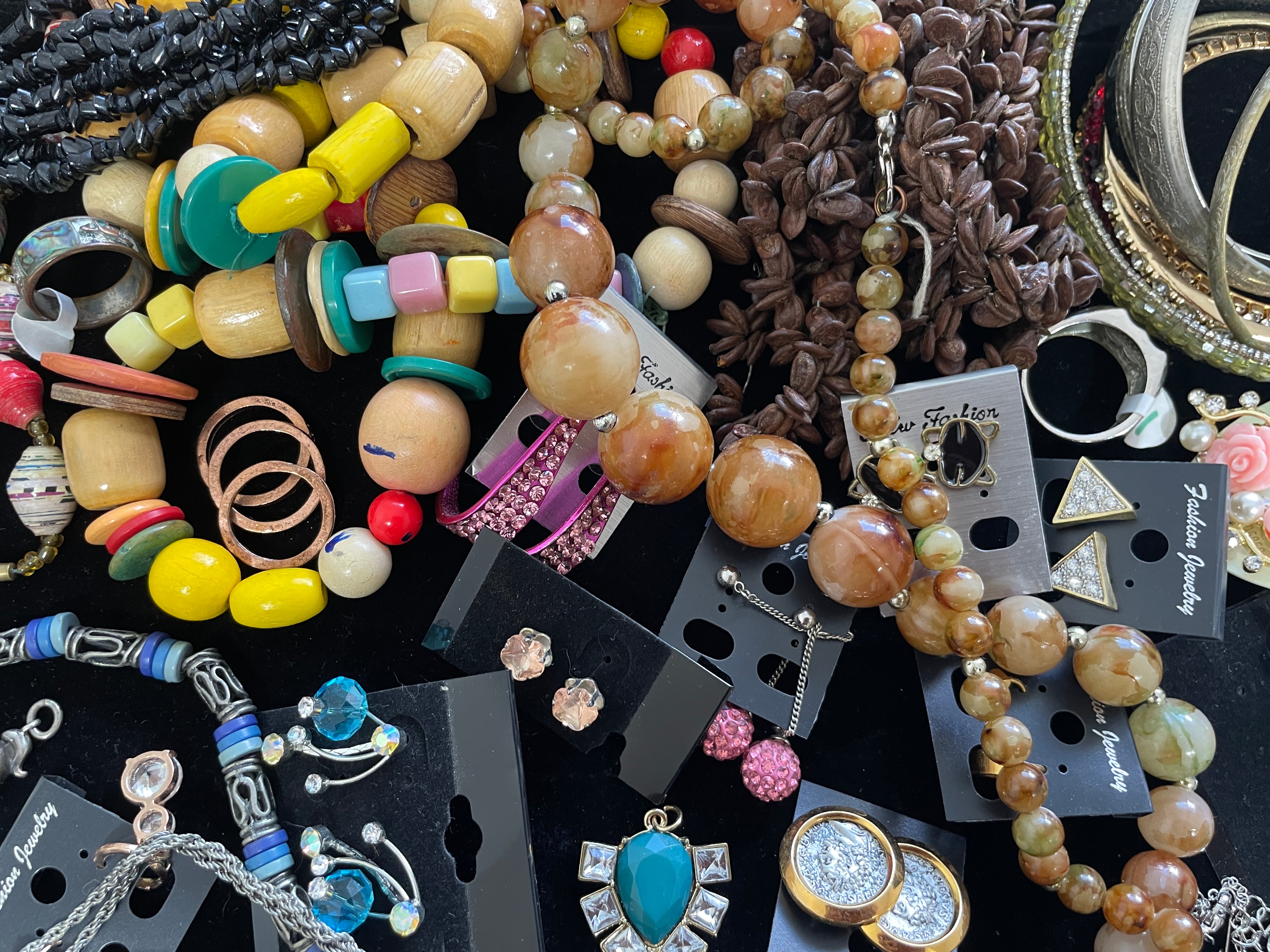 Assorted jewelry including beads and necklaces on a dark surface