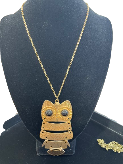 Gold necklace with a detailed owl pendant on a black stand