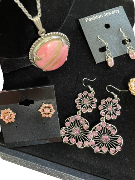 Jewelry set with pink pendant and earrings on a black surface
