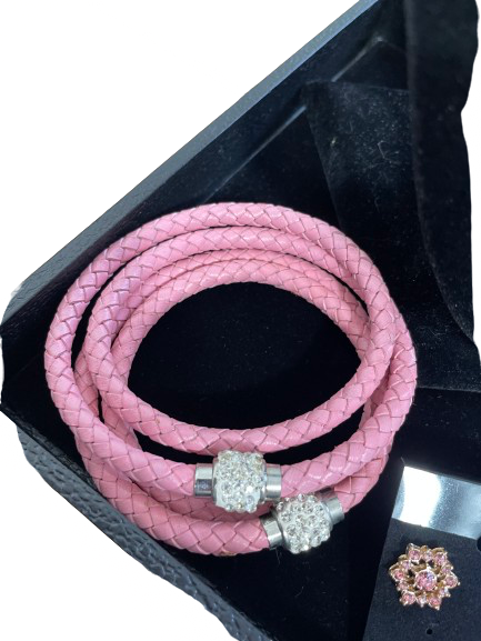 Pink braided bracelet with silver charms on a black background