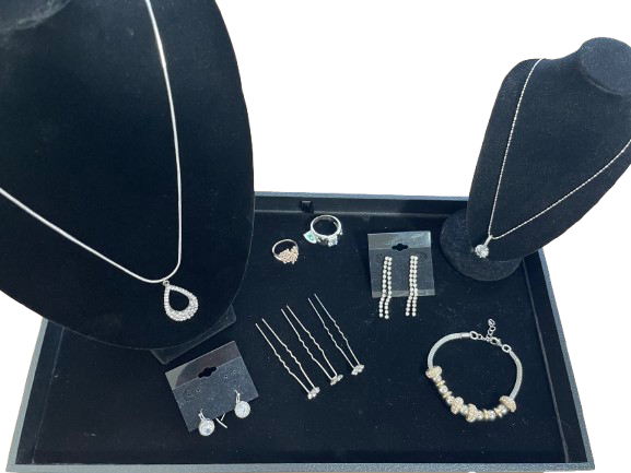 Collection of silver jewelry on a black jewelry box with black stands.