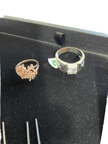Two rings on a black display stand with a ruler for size reference.