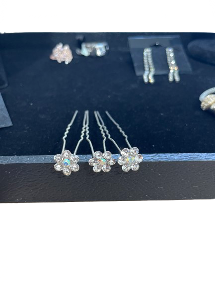 Set of silver hairpins with floral designs on a dark surface