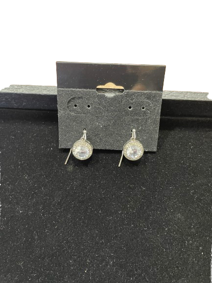 Pair of silver earrings with clear gemstones on a black card.