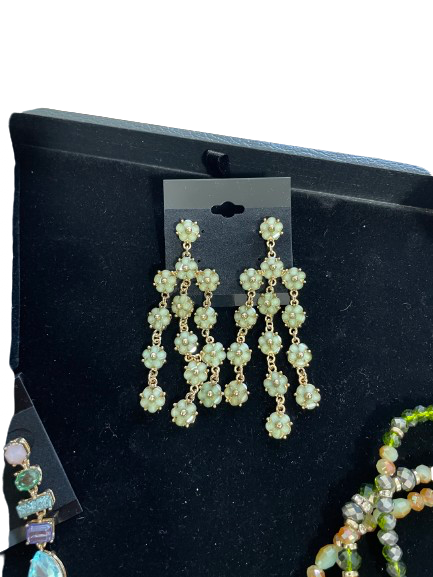 Green floral chandelier earrings on a black display card