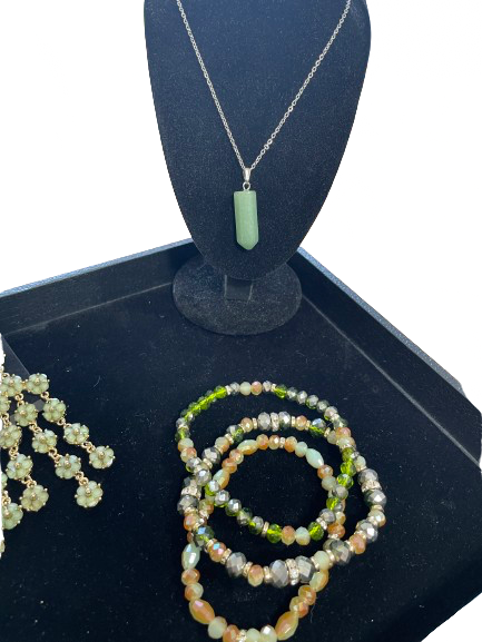 Jewelry set including a necklace, bracelet, and ring on a black stand with a white background