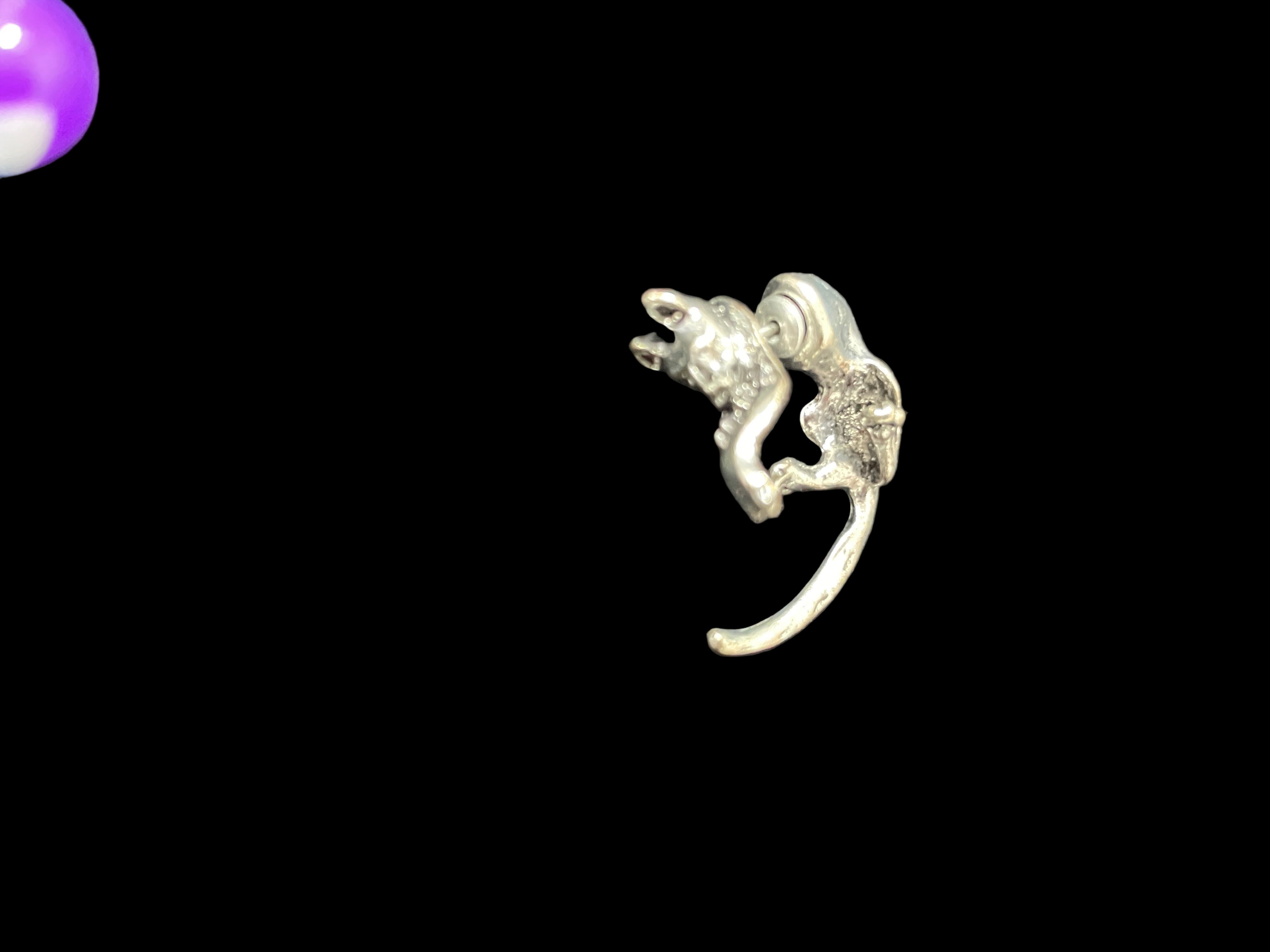 Silver cat-shaped navel ring on a dark surface