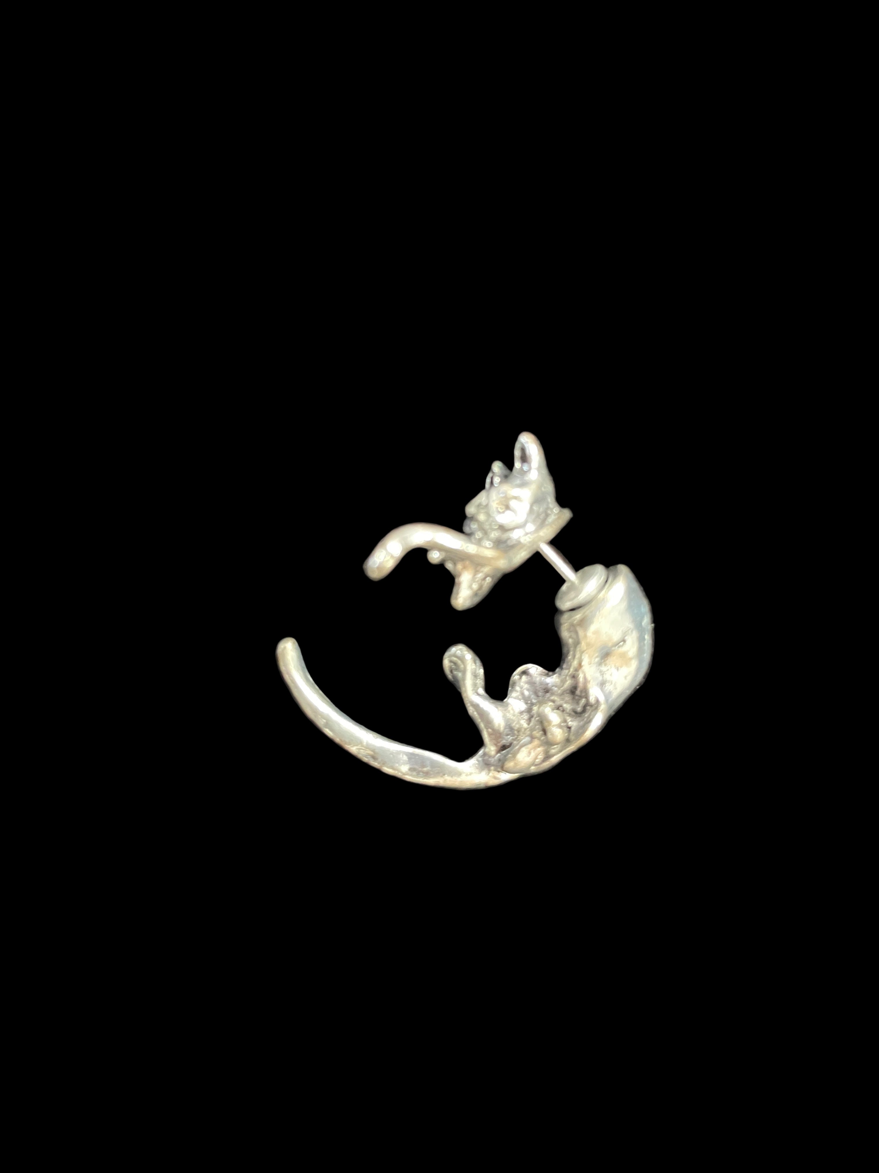Silver cat-shaped belly ring on a dark surface