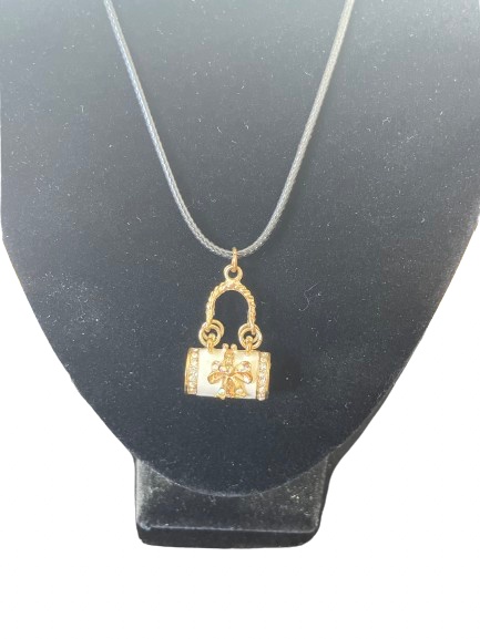 Gold purse-shaped pendant on a black stand with a white background