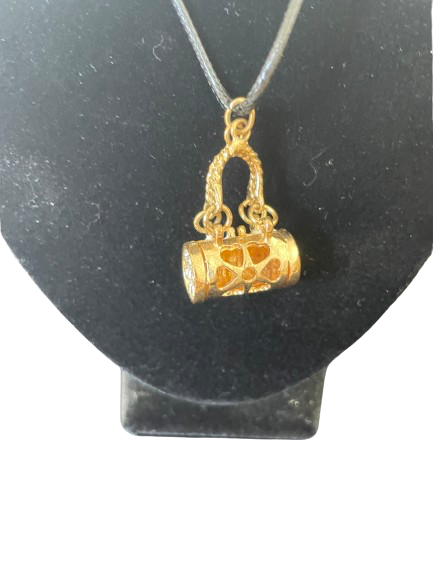 Gold pendant shaped like a purse on a black stand