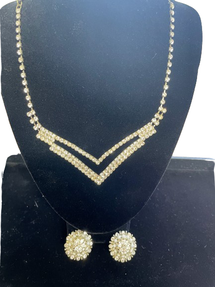 Vintage rhinestone necklace with V-shaped design and matching cluster earrings on display stand