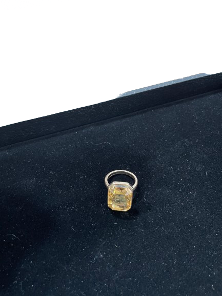 Ring with a yellow gemstone on a dark black background