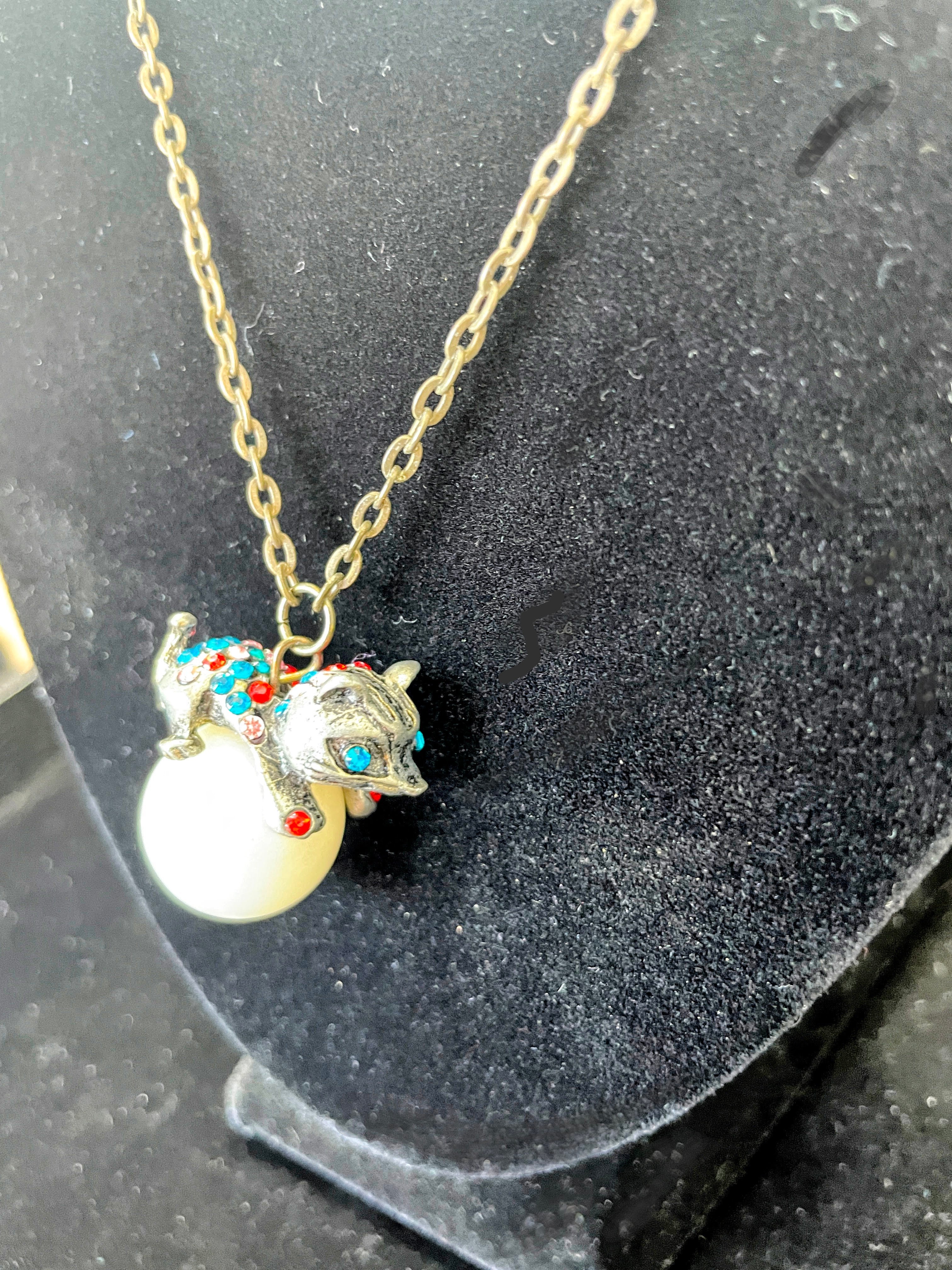 cat pendant with rhinestones on top of a pearl