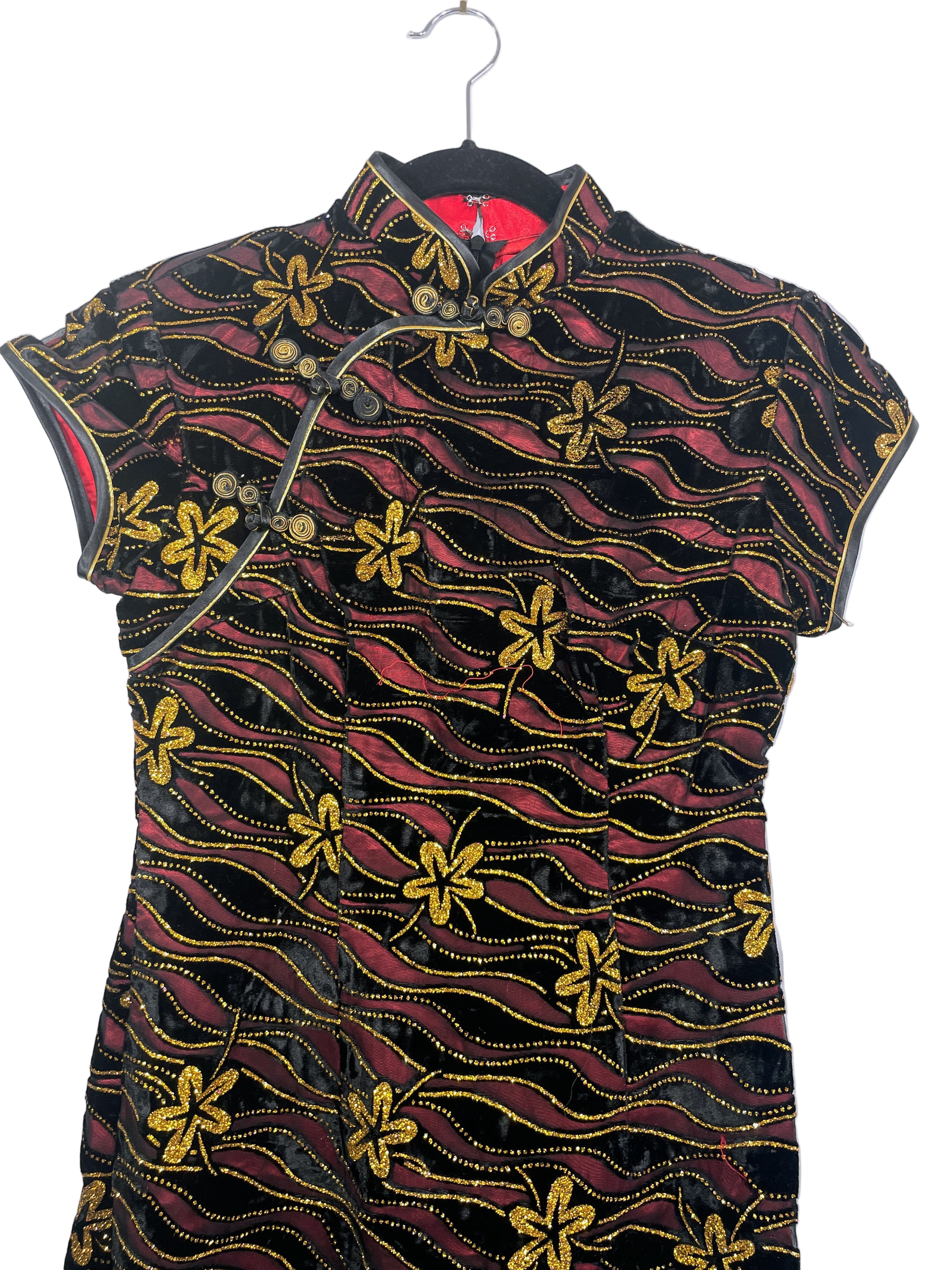 Traditional dress with black, red, and gold pattern on a white background