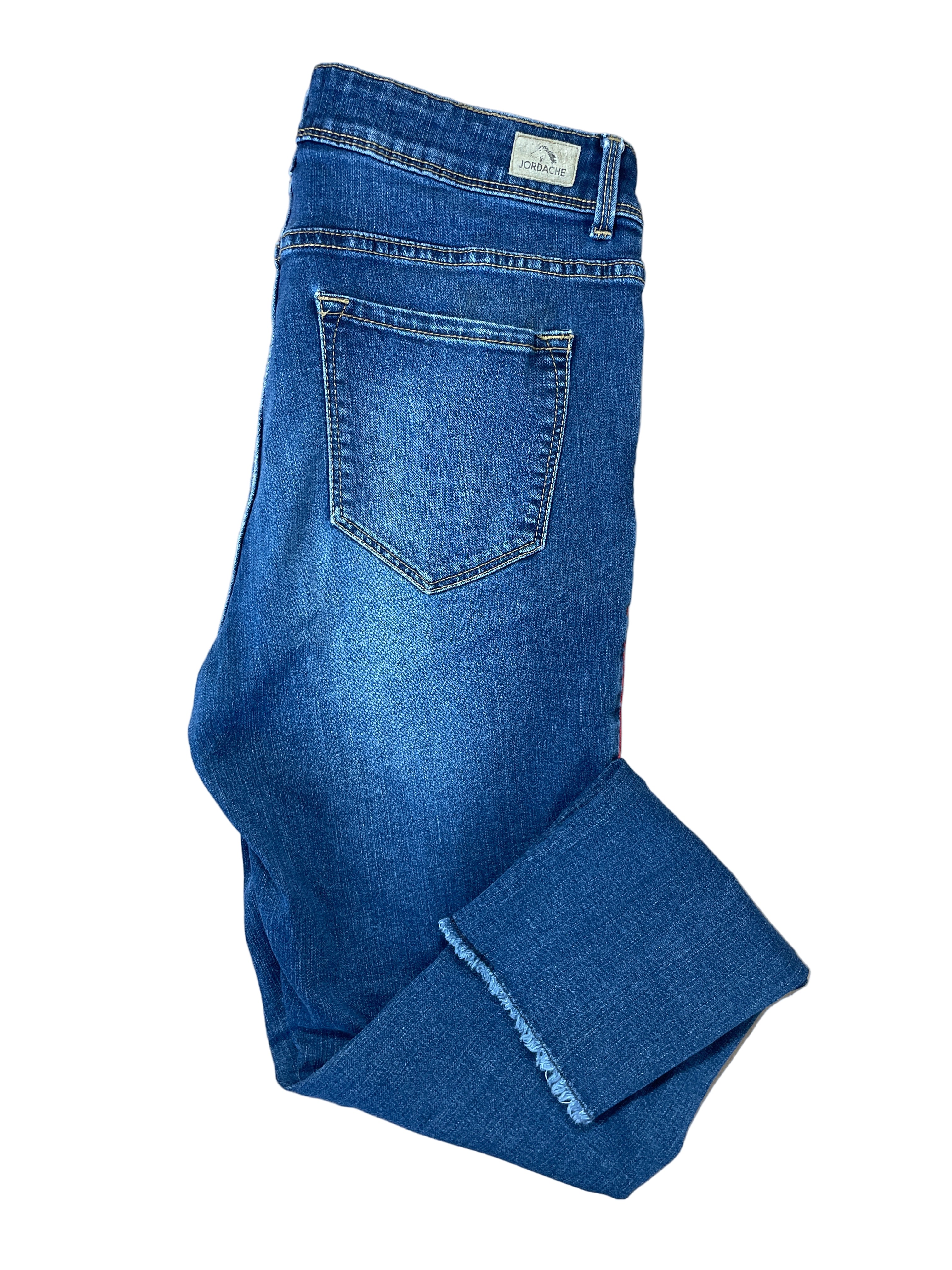 Folded view of Jordache high rise ankle skinny jeans medium wash with red piping and frayed hem