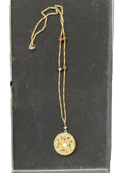 Gold-tone filigree necklace with round rhinestone pendant displayed flat