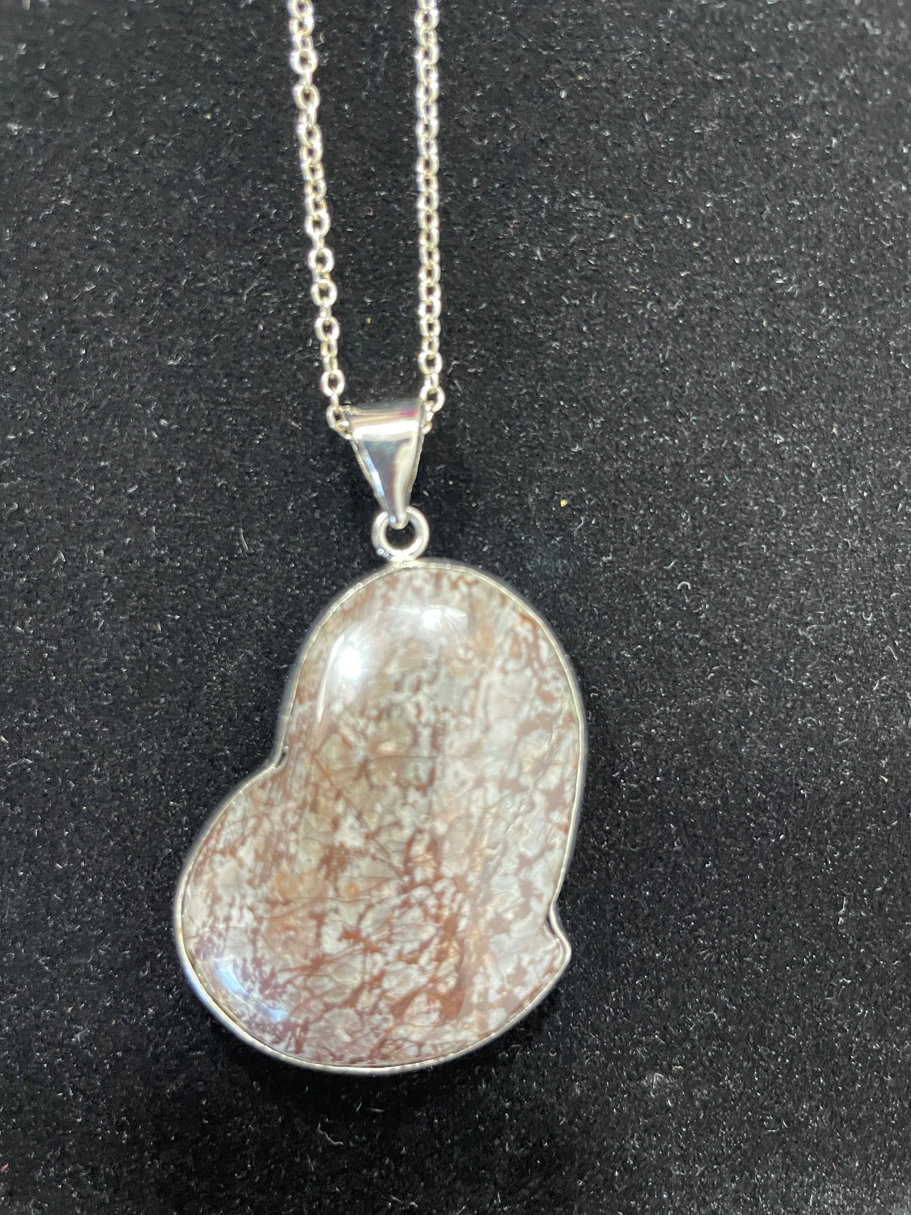 Silver pendant necklace on a black background