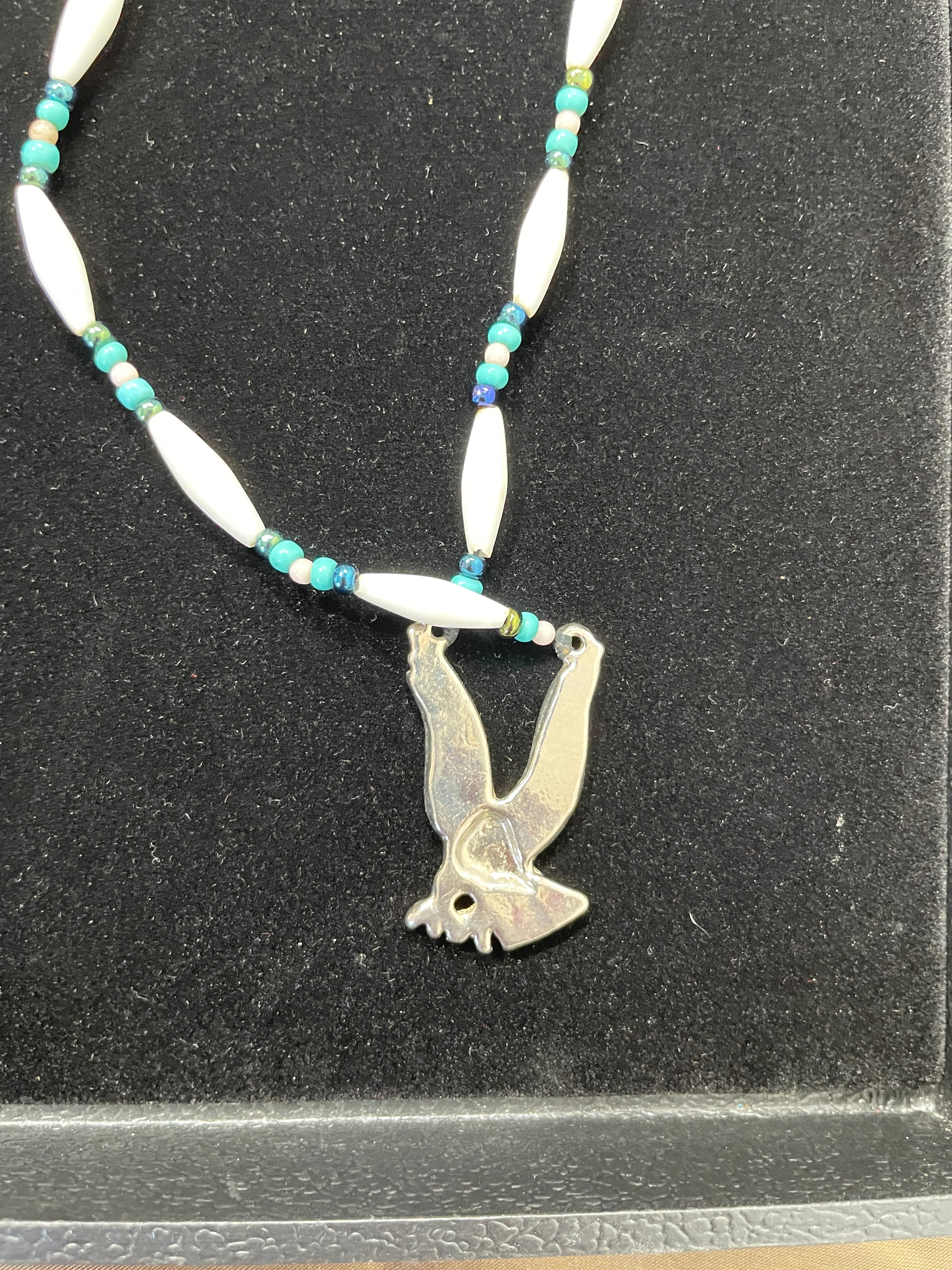 Necklace with a silver fish pendant on a black background