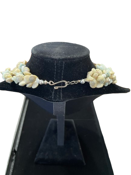 shell ecklace on a black mannequin bust against a white background