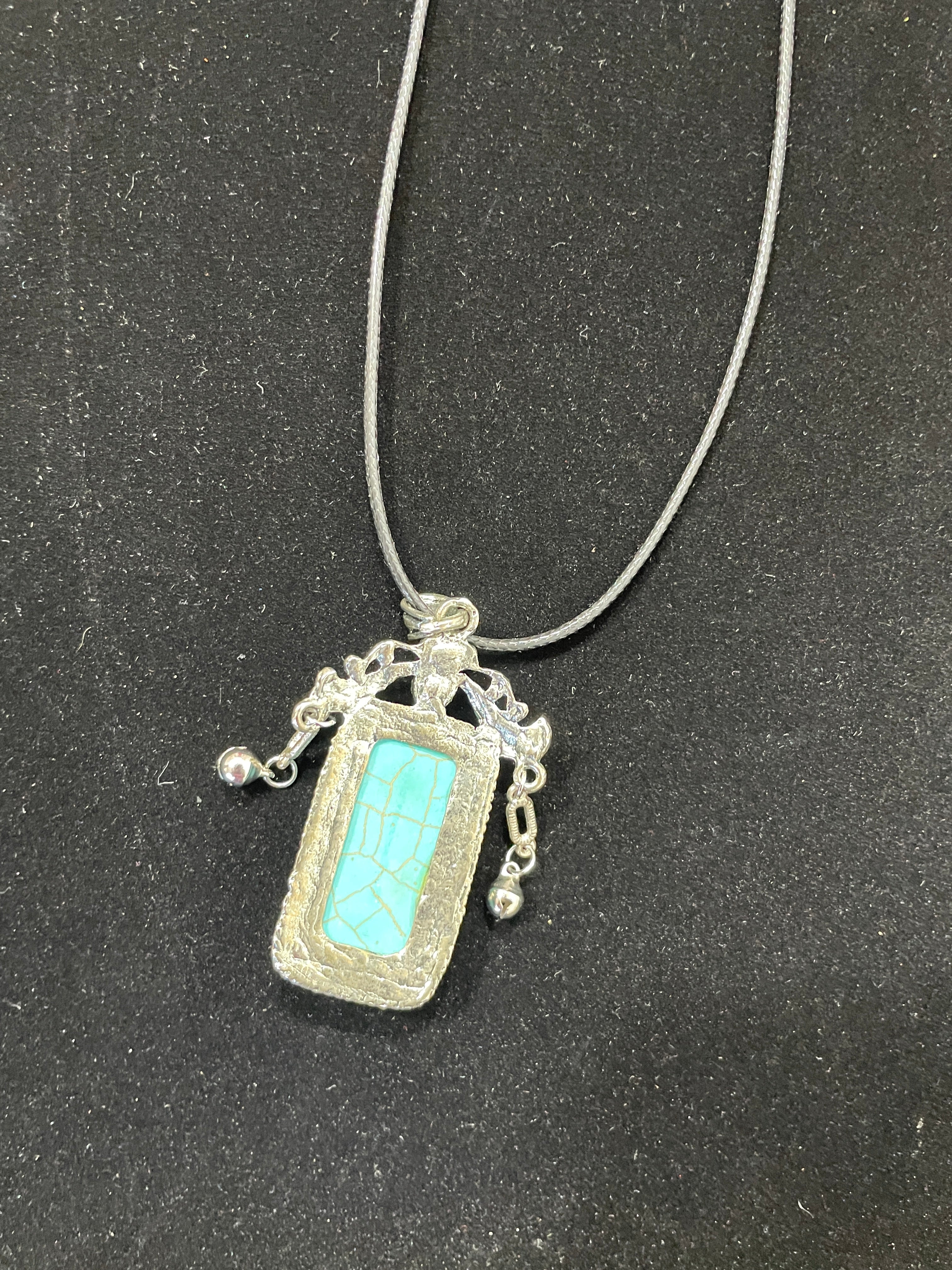 Necklace with a pendant featuring turquoise stone on a black background